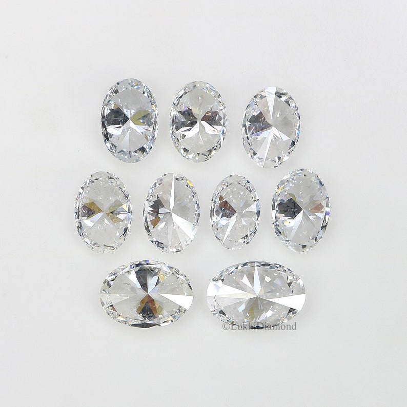 May include: Eight clear oval-shaped gemstones with a faceted design. The gemstones are arranged in two rows on a white background.