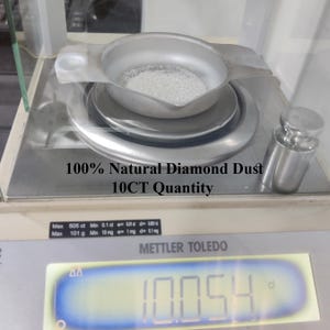 Pu&ograve; includere: Una vaschetta di pesata in metallo argentato contenente polvere di diamante fine, bianca e granulare, posizionata su una bilancia digitale Mettler Toledo. Il display mostra 10,054 ct. Il testo recita 100% Natural Diamond Dust 10CT Quantity.