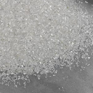 Pu&ograve; includere: Una grande collezione di piccoli frammenti di conchiglia frantumati, traslucidi, bianchi e iridescenti. I pezzi sono di forma irregolare, di dimensioni variabili e possiedono una texture superficiale madreperlacea e riflettente che cattura la luce.