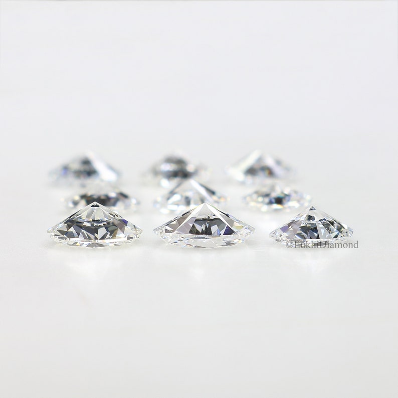 May include: A group of eight clear, round, faceted diamonds on a white background.