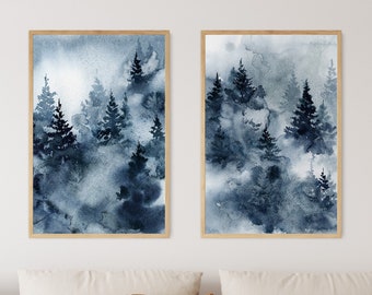 May include: Two framed watercolor paintings depict a misty forest scene in shades of blue and gray. The artwork features silhouetted evergreen trees, creating a serene and natural aesthetic. The frames are a light brown color.