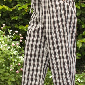 Pu&ograve; includere: Pantaloni a quadri neri e bianchi con vita a coulisse. I pantaloni sono a gamba larga e hanno una vestibilit&agrave; rilassata.