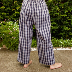 Pu&ograve; includere: Un paio di pantaloni da pigiama a quadri blu e bianchi con elastico in vita.