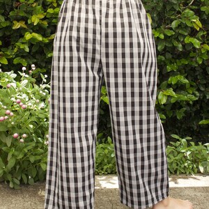 Pu&ograve; includere: Pantaloni a gamba larga a quadri neri e bianchi con elastico in vita.