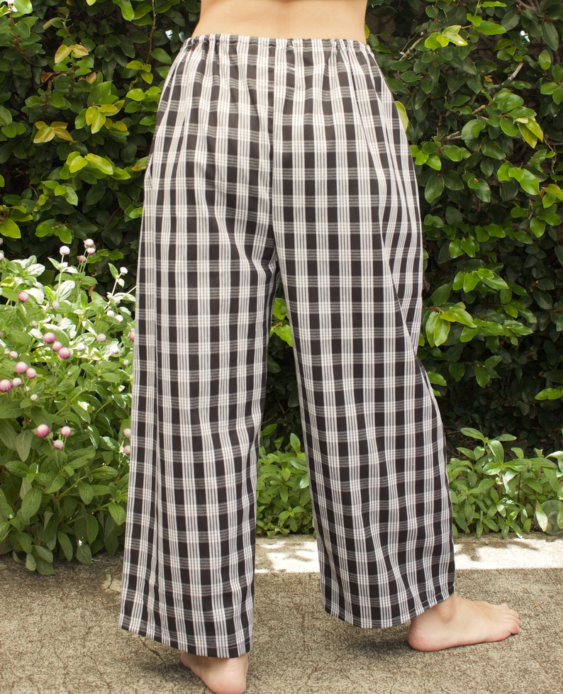 Pu&ograve; includere: Pantaloni a gamba larga a quadri neri e bianchi con elastico in vita.