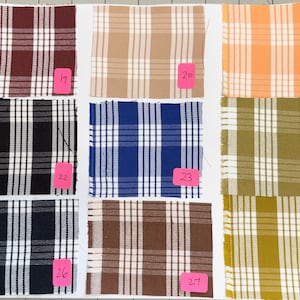 May include: A grid of nine fabric swatches featuring various plaid patterns in colors including maroon, tan, orange, black, blue, olive green, navy, and brown. Each square swatch is labeled with a pink tag numbered from 19 through 27.