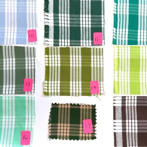May include: A collection of nine square fabric swatches featuring various plaid patterns in shades of blue, green, lime, olive, and brown. Each swatch is labeled with a pink tag numbered 10 through 18, displaying white grid lines.
