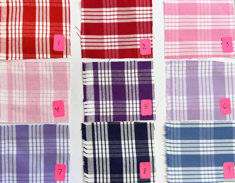 May include: Nine fabric swatches arranged in a grid, each featuring a white plaid pattern. The colors include red, pink, purple, and blue shades. Each swatch is labeled with a pink tag numbered one through nine, indicating distinct color variations.