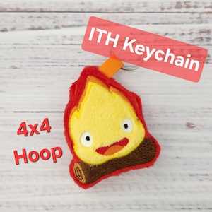 May include: A plush keychain featuring a cartoon flame character with a smiling face. The flame is primarily yellow with red and orange accents. The keychain includes the text "ITH Keychain" and "4x4 Hoop".