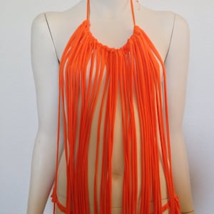 May include: Orange halter top with fringe detail. The top is made of a soft, stretchy fabric and has a relaxed fit.