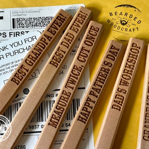 May include: Five wooden pencils with different engraved messages. The messages are "Best Grandpa Ever!", "Best Dad Ever!", "Measure Twice, Cut Once", "Happy Father's Day", "Dad's Workshop", and "Grandpa's Workshop".