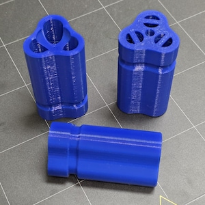 May include: Three blue 3D-printed objects. Two are cylindrical with a three-lobed top, one with holes and the other with open sections. The third is a rectangular shape with a similar blue color and texture.