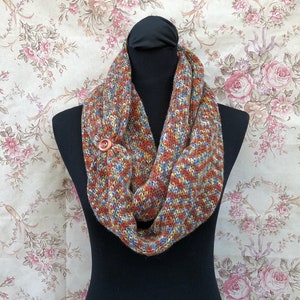 May include: A brown, blue, and yellow infinity scarf with a wooden button. The scarf is made of a soft, knitted fabric.