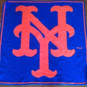 May include: A blue crocheted blanket with a large orange "NY" logo in the center.