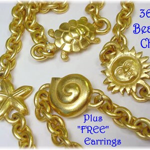 May include: A 36" gold-tone chain necklace featuring charms of a turtle, a sun, a starfish, and a spiral seashell. The text "36" Beach Chain" and "Plus "FREE" Earrings" is printed in blue on the image. The chain has thick, rounded links.
