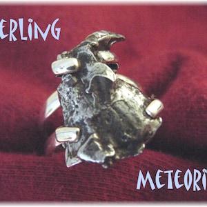 May include: Sterling silver ring featuring a meteorite fragment. The ring is set with a rough, dark gray meteorite piece and has a polished silver band.