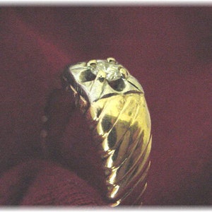 May include: A gold ring with a single diamond set in the center. The ring has a textured, twisted band.