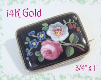 May include: A 14K gold brooch with a black enamel background and a colorful floral design. The brooch is 3/4 inch by 1 inch.
