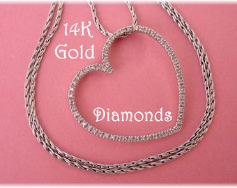May include: A silver necklace with a heart-shaped pendant. The pendant is encrusted with diamonds and is surrounded by a silver chain. The words "14K Gold Diamonds" are written on the image.
