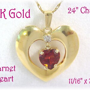 May include: A 14K gold pendant necklace with a large heart-shaped frame and a smaller garnet heart inside. The pendant is attached to a 24-inch chain. The pendant measures 1 1/16 inches by 7/8 inches.