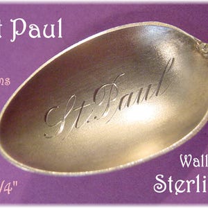 May include: A silver spoon with the engraved text "St. Paul" in the bowl. The spoon is 3 3/4 inches long and weighs 8 grams. The text "Wallace Sterling" is also visible. The spoon has a decorative handle.