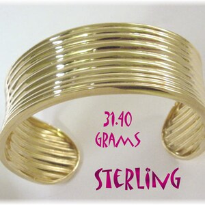 May include: A gold-toned sterling silver bangle bracelet with a ridged design. The bracelet weighs 31.40 grams.