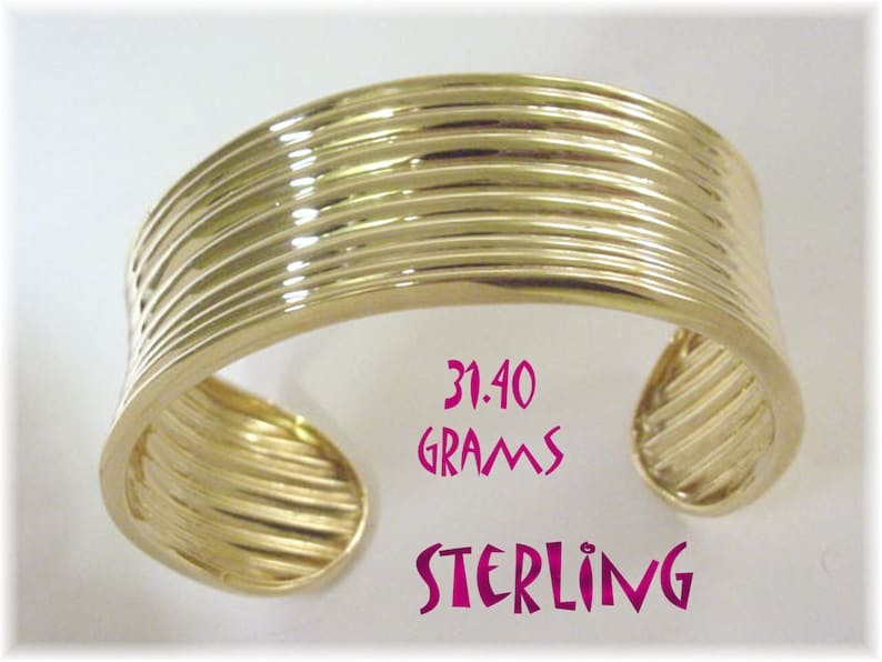 May include: A gold-toned sterling silver bangle bracelet with a ridged design. The bracelet weighs 31.40 grams.