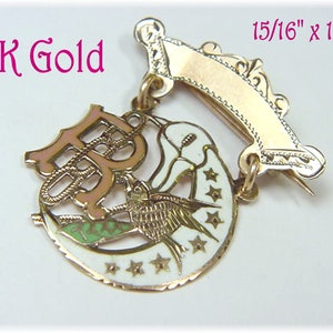 May include: A 10K gold pin with a crescent moon design, a bird, and a letter 'B' in pink enamel. The pin is 15/16 inches by 1 1/8 inches.