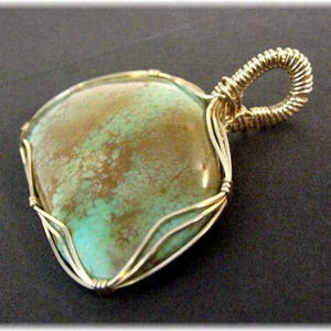 May include: A turquoise gemstone pendant with a gold wire wrap. The stone has a mottled green and brown pattern.