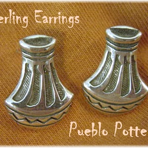 May include: Two sterling silver earrings with a Pueblo Pottery design. Each earring has a flared, vase-like shape with etched details and a zig-zag pattern at the base. The text "Sterling Earrings" and "Pueblo Pottery" are visible.