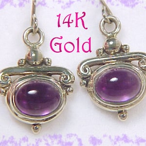 May include: Silver-coloured earrings featuring oval, deep purple gemstones. The earrings have a decorative design with scrollwork and small, round accents. The text "14K Gold" is visible in pink.