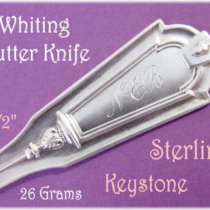 May include: A sterling silver butter knife with the text "Whiting Butter Knife" and "Keystone". The knife is 6 1/2 inches long and weighs 26 grams. Features an engraved monogram and decorative details.