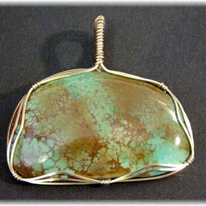 May include: A turquoise pendant with a gold wire wrap. The turquoise is a mottled green and brown color.