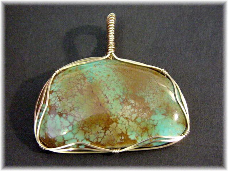 May include: A turquoise pendant with a gold wire wrap. The turquoise is a mottled green and brown color.