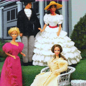 May include: Four crochet dolls dressed in vintage clothing. A woman in a white dress with a yellow hat, a woman in a pink dress, a woman in a yellow dress, and a man in a black suit and gray pants.