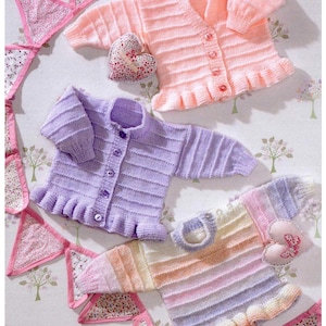 May include: A collection of knitted baby cardigans in pastel colors: peach, lavender, and a rainbow gradient. Each cardigan features a ruffled hem and button closure. Decorative heart-shaped pillows and a pink floral banner complete the scene.