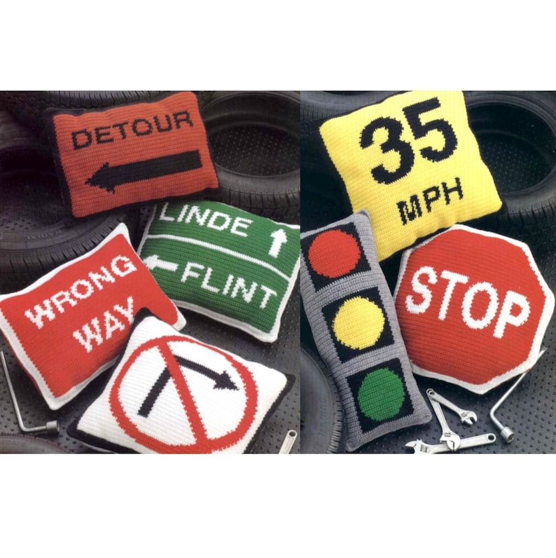 K&ouml;nnte beinhalten: Sechs gestrickte Kissen in Form von Verkehrsschildern. Die Schilder beinhalten "Umleitung", "Falsche Richtung", "Linksabbiegen verboten", "Linde Flint", "35 MPH" und "Stopp".