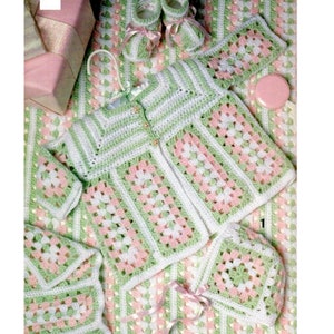 May include: A handmade crochet baby set in white, light green, and pink. The set includes a jacket, hat, booties, blanket, and a small square. The granny square design is visible throughout the set.