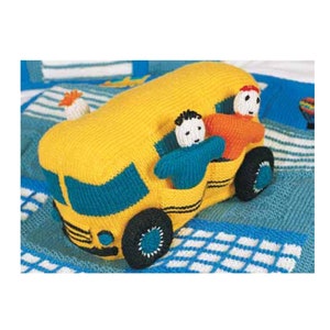 May include: A yellow knitted school bus toy with two children inside. The bus has black wheels and a blue windshield. The children are wearing blue and orange sweaters.