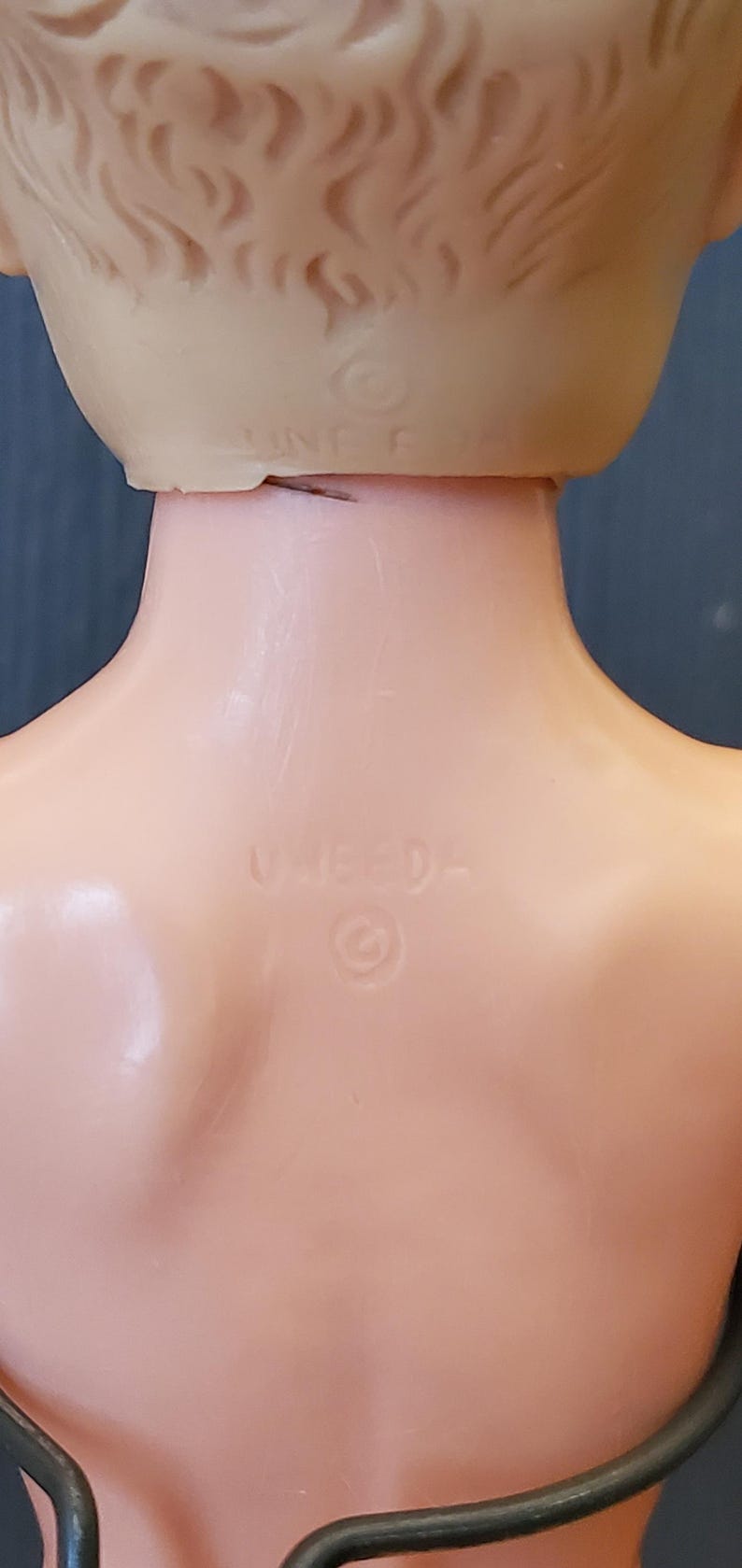 May include: Close-up of the back of a doll's head, showing a copyright symbol and the text "UN-ED-".