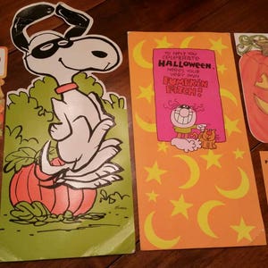 May include: A set of five Halloween-themed greeting cards. The cards feature a cartoon dog, a pumpkin, a jack-o-lantern, and a child dressed as a pumpkin. The cards are all orange and yellow with black and white accents. The text on the cards reads "To help you celebrate Halloween", "Happy Halloween", "For a special boy", "Mr. Pumpkin", and "Eat, Drink and Be Scary!"