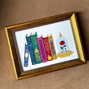 Può includere: Stampa incorniciata con una serie di libri illustrati con copertine decorative. I libri sono in vari colori, tra cui blu, verde, viola e rosso. Una cupola di vetro con una rosa rossa è a destra. La cornice è dorata.