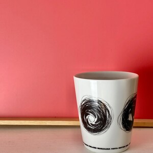 May include: White ceramic mug with black abstract designs and the text "FINLAND MARJAANA VIRTA MOTOR 2001".