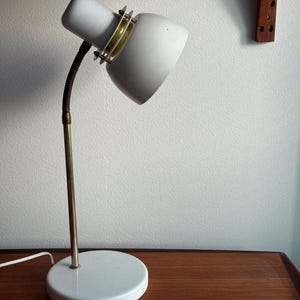 Vintage table lamp from 1970s by the Swedish company Belid. The lamp is made of metal painted white and features golden metal