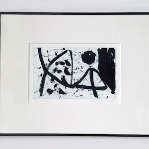 May include: Black and white abstract art print with a white background and black ink splatters and lines. The print is framed in a black frame.