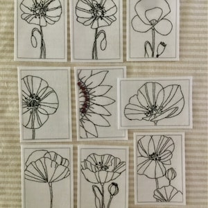 May include: Nine black and white line drawings of flowers on white card stock. The flowers are poppies and a sunflower. The drawings are simple and elegant.