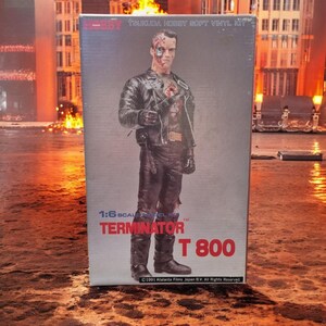 May include: A box for a 1:6 scale soft vinyl kit of the Terminator T-800. The box features a photo of the Terminator in a black leather jacket and jeans. The text on the box reads "Teukuda Hobby Soft Vinyl Kit 1:6 Scale Model Kit Terminator T 800 ©1991 Atalanta Films Japan B.V. All Rights Reserved."