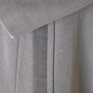 May include: Close-up of a black fabric with a vertical seam and a black fabric pocket.