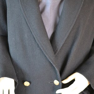 May include: A black double-breasted coat with gold buttons. The coat is made of a soft, textured fabric.