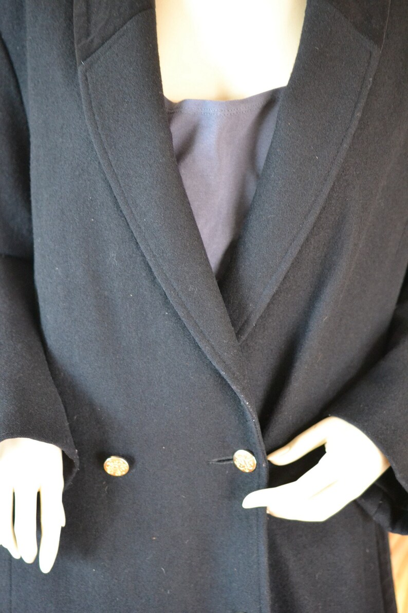 May include: A black double-breasted coat with gold buttons. The coat is made of a soft, textured fabric.